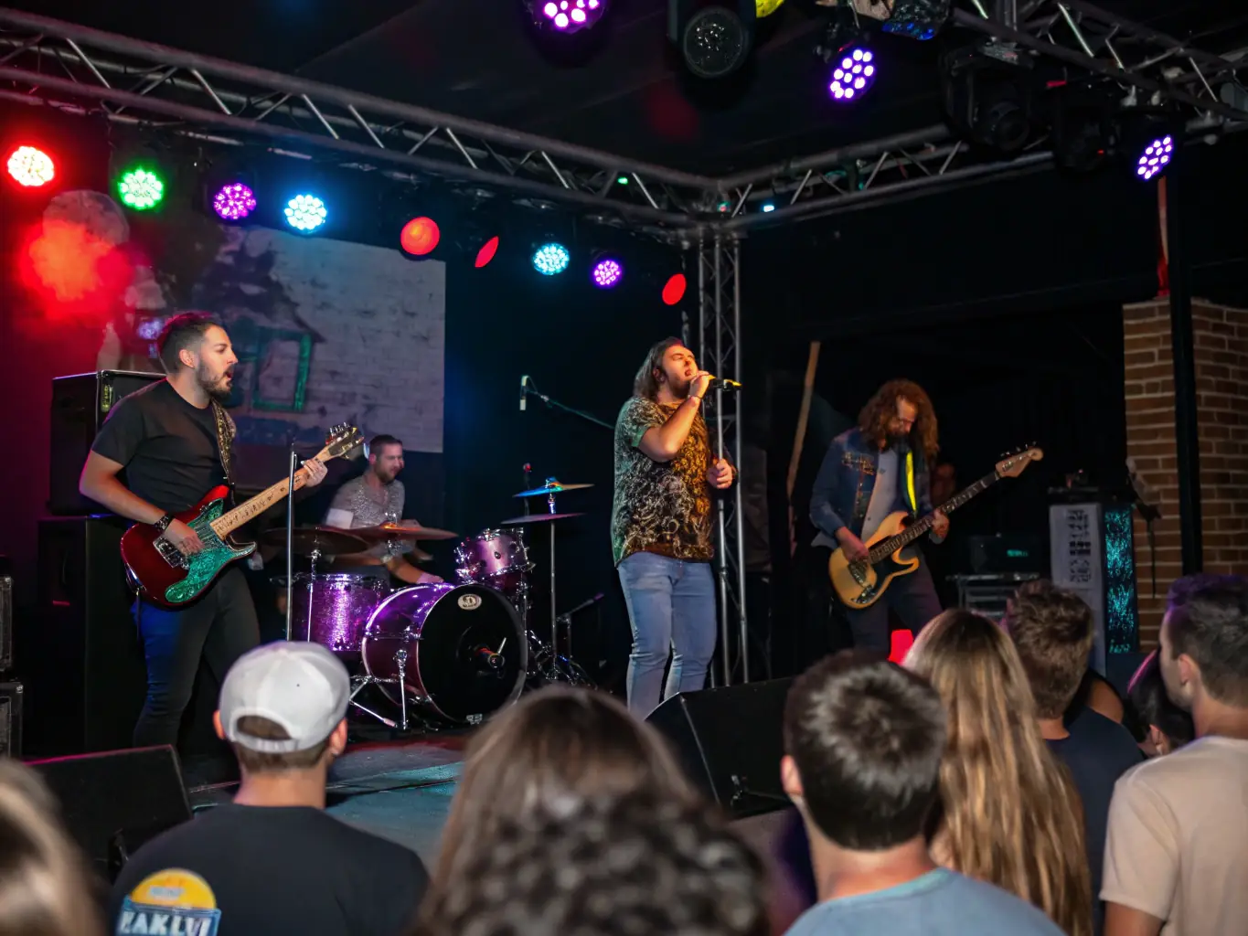 A vibrant image of a live music performance at a POULPERIE PROD event, showcasing musicians on stage with an enthusiastic audience in the background. The image captures the energy and excitement of a live performance, highlighting the organization's commitment to supporting musical talent.